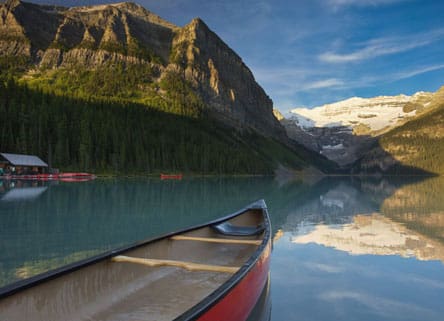 Canoe on a calm lake with mountains.