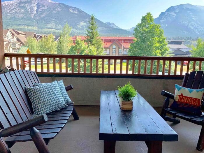 Mountain view balcony with furniture and plants.